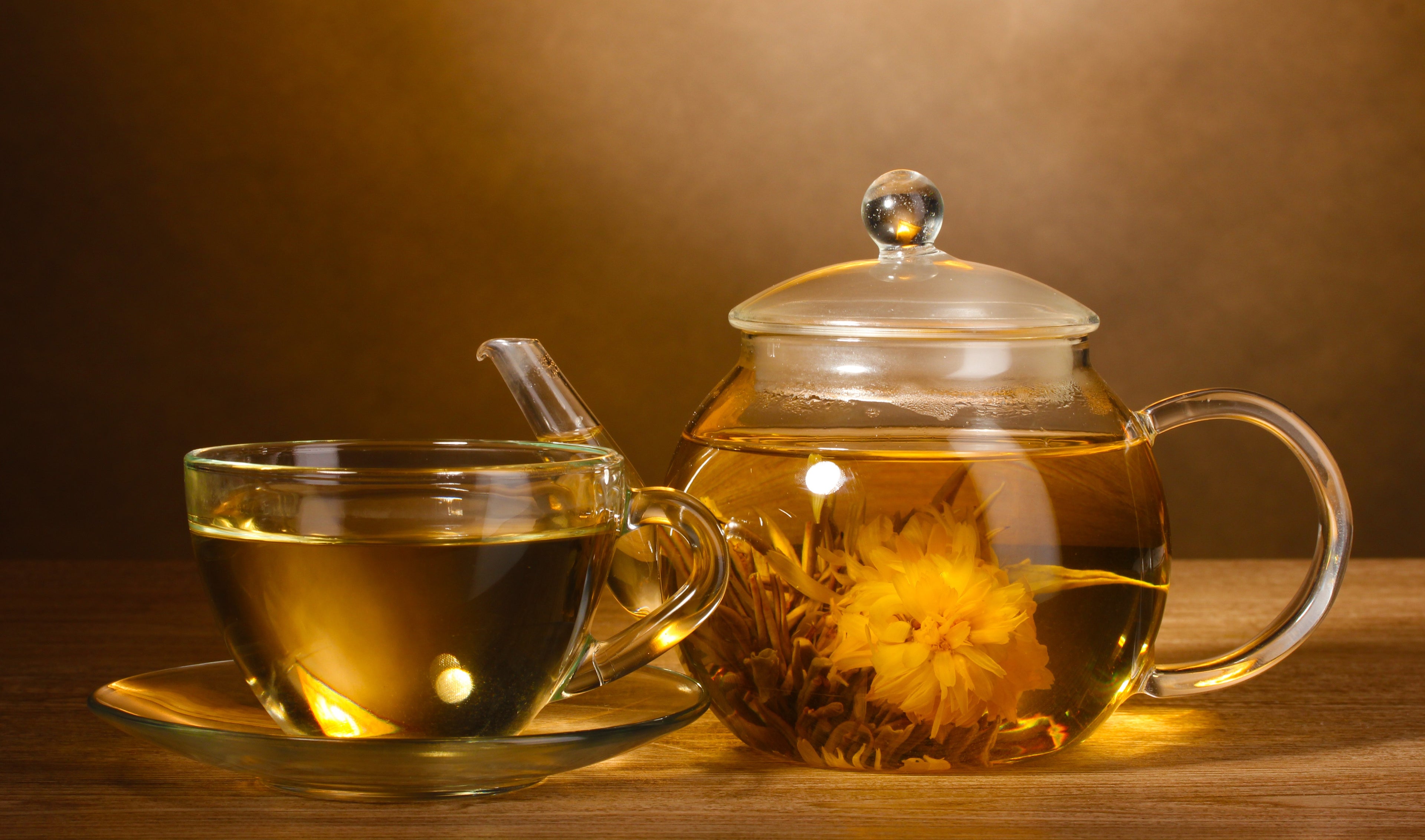 a glass teapot with blossoming green tea leaves