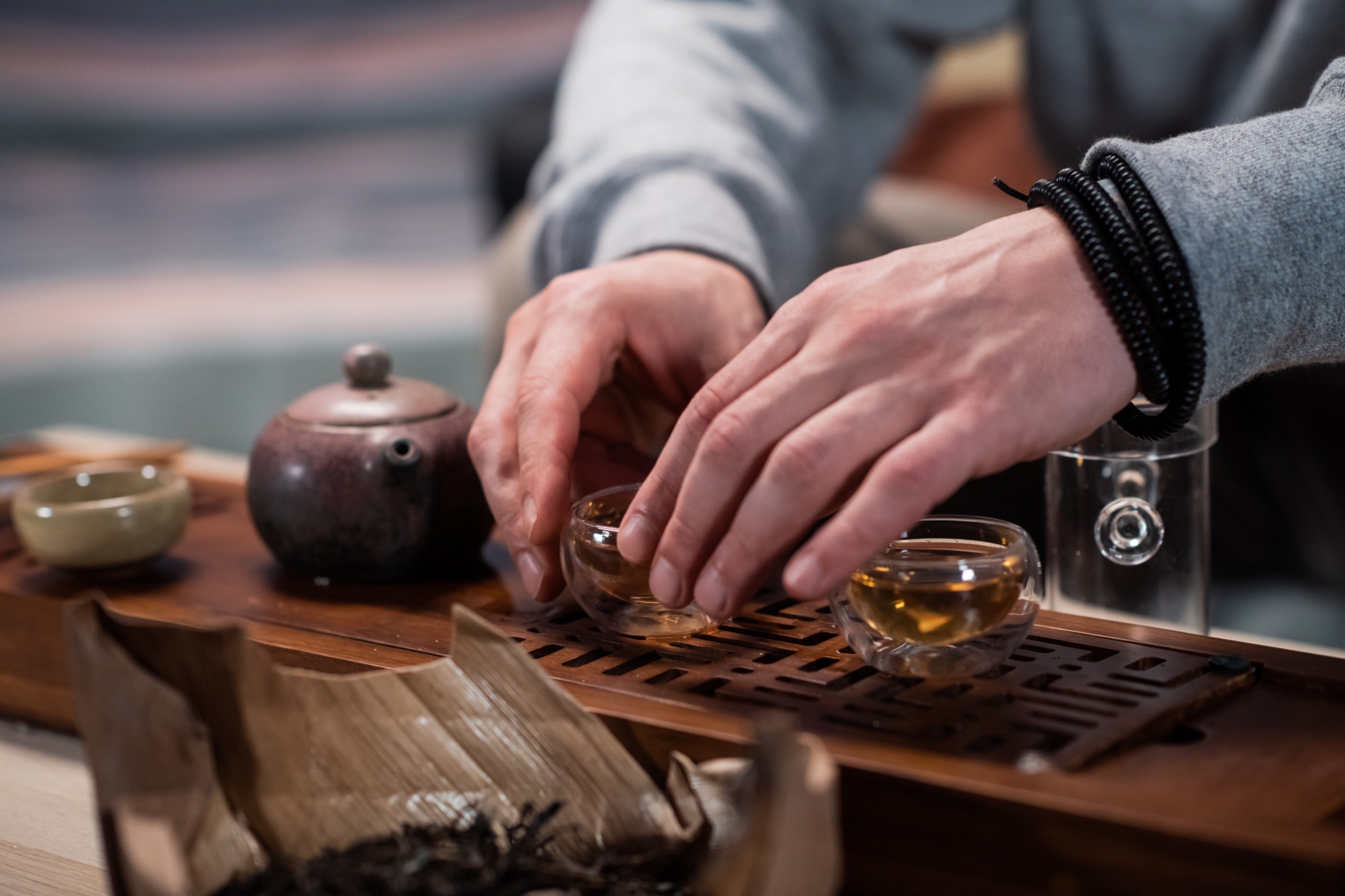 man brewing tea using a traditional clay pot