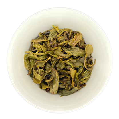 White bowl filled with the steeped leaves of jasmine green tea on a white background